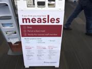 A pedestrian walks past an informational sign about the measles in the entrance of the Kaiser Permanente Cascade Park office Monday morning, Feb. 4, 2019.