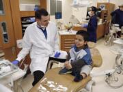 Dr. Joseph Kelly, left, chats with 9 year-old Samuel Pena, right, at a free children’s dental clinic held Saturday at Clark College.