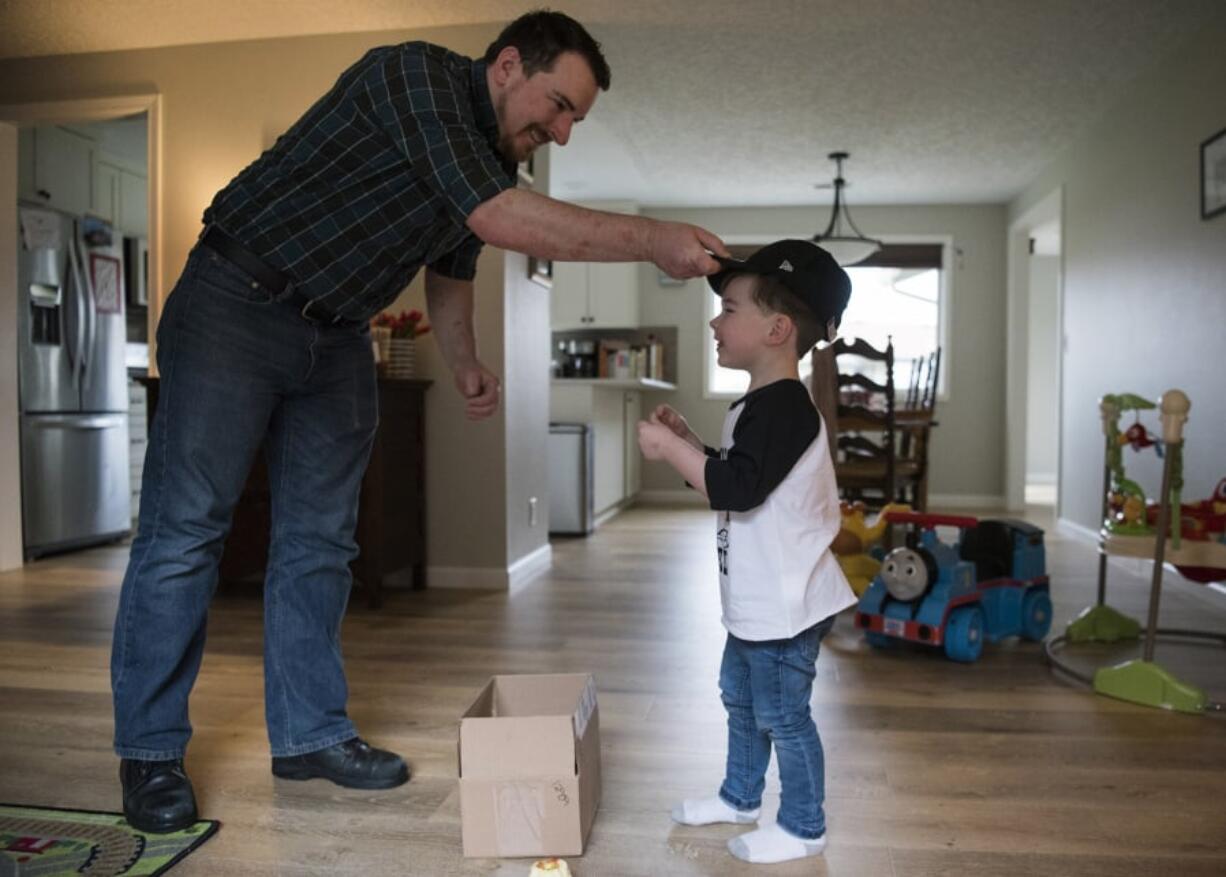 Ian Goss gives his son, Shep, a Colorado Rockies hat for his third birthday Friday at their home in Vancouver. Ian and his wife, Christina, had a birthday party planned for Shep over the weekend but canceled it because of the recent measles outbreak. Shep has his first vaccination, but their 4-month-old daughter Faye is too young to get the immunization.