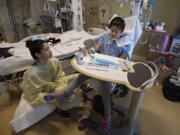 Physical therapist Janine Vizon, left, works on the feet of DejaRay Smith, 13, of Washougal as she also takes part in art therapy at Randall Children’s Hospital in Portland. DejaRay has been battling a MRSA infection for 59 days at Randall.