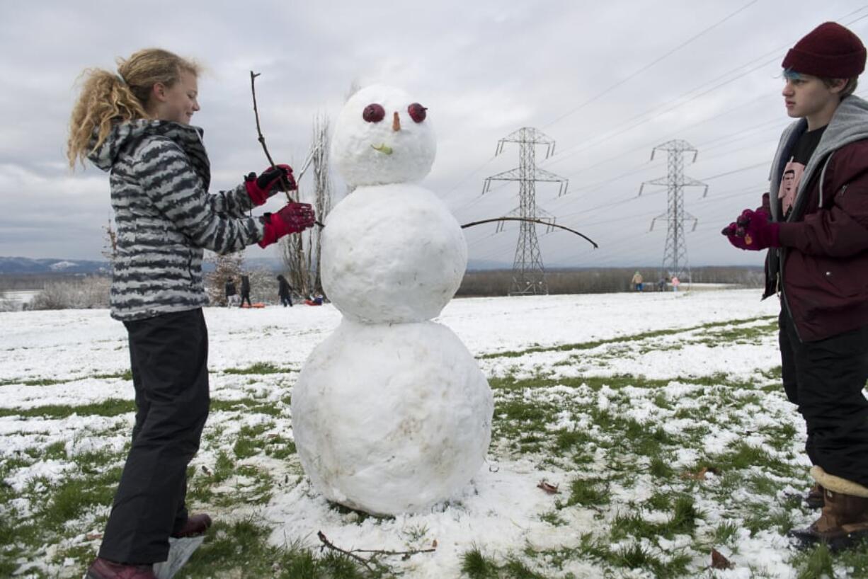 Zoe Anderson, 11, and Matthew Schilling, 17, both of Portland, make a snowman in Franklin Park in Vancouver on Saturday.