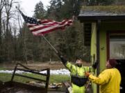 Ridgefield Public Works employee Nick Johnson, left, and James Barhitte, caretaker at Abrams Park in Ridgefield, move an American flag that was blocking a rain gutter on a park building Tuesday.