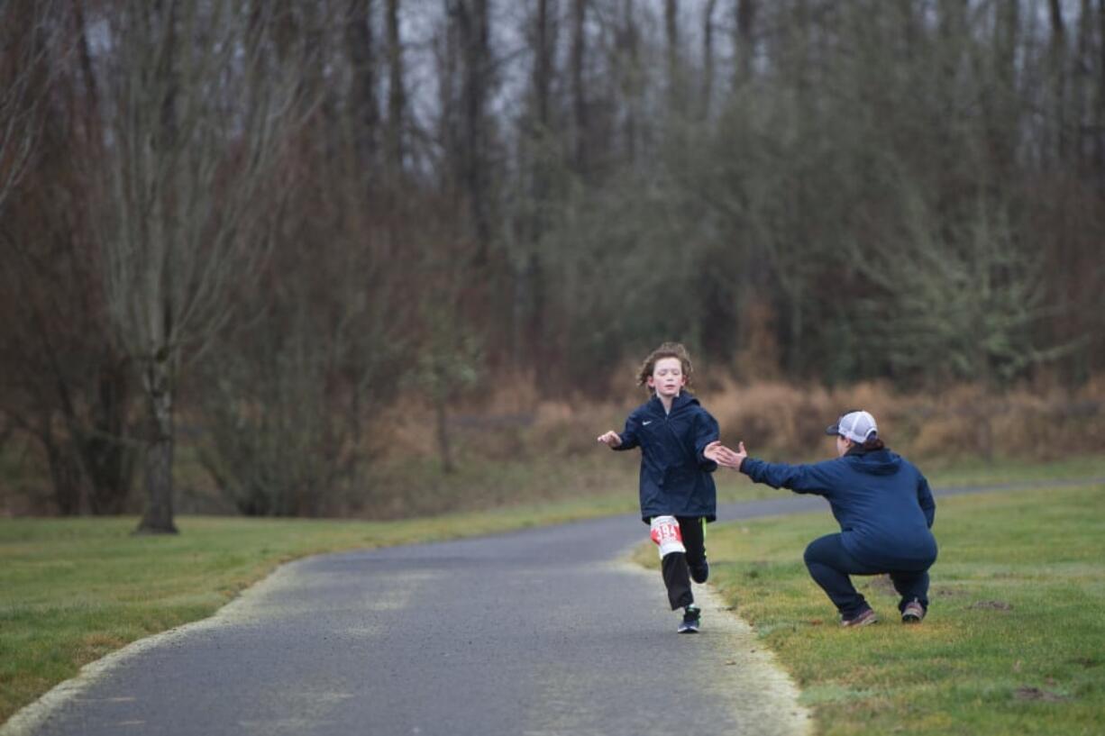 Jennifer Lyman high-fives Jackson Thibert, 10, as he completes a four-mile race as part of the Vancouver Lake Half Marathon on Sunday morning.