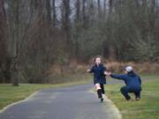 Jennifer Lyman high-fives Jackson Thibert, 10, as he completes a four-mile race as part of the Vancouver Lake Half Marathon on Sunday morning.