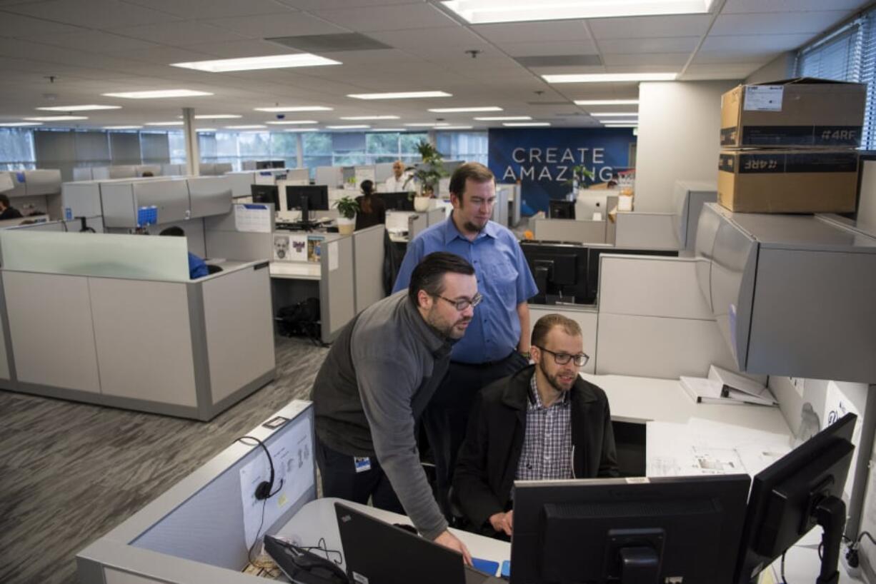 Jimmy Carr, drafting technician, from left, Rob Butler, drafting technician, and John Hofman, staff engineer, look over project plans at Burns & McDonnell in Vancouver. The office recently added 3,200 square feet of space.