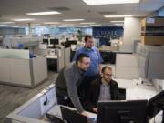 Jimmy Carr, drafting technician, from left, Rob Butler, drafting technician, and John Hofman, staff engineer, look over project plans at Burns & McDonnell in Vancouver. The office recently added 3,200 square feet of space.