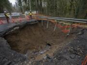 Clark County Public Works spokesman Jeff Mize, left, and bridge and culvert manager Ken Price look over a collapsed section of Northwest Pacific Highway in La Center. The road has been closed since Feb. 12 and is expected to remain closed for a few months while the county works to repair it.