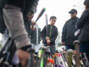 Ethan Le, 12, gets advice Sunday while picking out a baseball bat during a used baseball gear distribution event at Clark College. The event was organized by the Good Sport Equipment Connection and supported by groups including the Police Activities League.