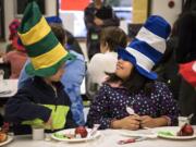 Martin Luther King Elementary School first-graders Vova Chygasov, left, and Jacky Jaca goof around with their Dr. Seuss hats during a green eggs and ham breakfast at Martin Luther King Elementary School in Vancouver on Wednesday. Beaches Restaurant & Bar owner Mark Matthias and a team of volunteers are feeding green eggs and ham — inspired by the book of the same name — to first-graders and their parents at elementary schools in the Vancouver and Evergreen districts, as well as other county schools throughout the week.