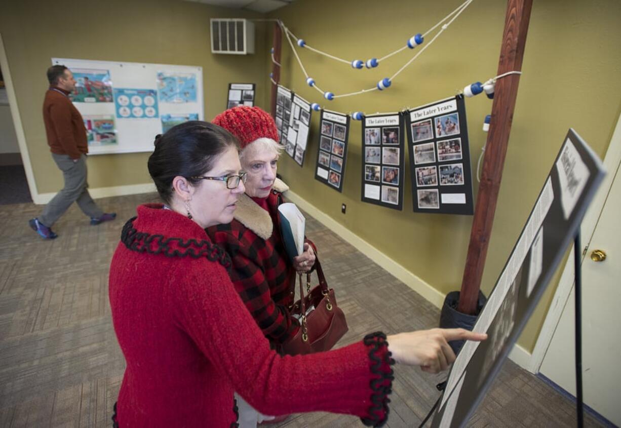 Krista Bashaw, red sweater, Camas Parks and Recreation special events coordinator, looks over photos and information about the Crown Park pool with former lifeguard Beverly Seagraves as they celebrate the history of the pool, which opened in 1954 and closed in 2017.