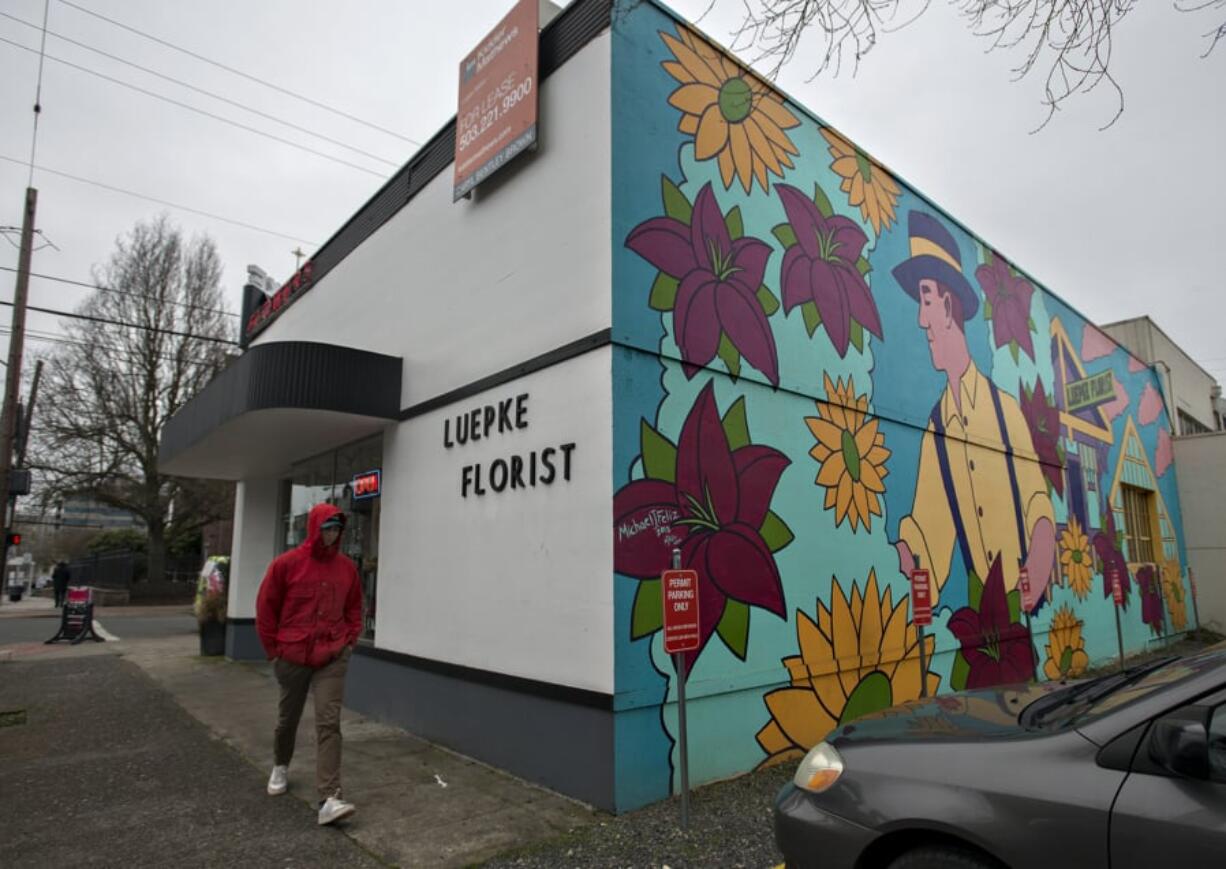 Cole Wyckoff of Vancouver strolls past Luepke Flowers and Finds on Wednesday afternoon. The business closed today. The Luepke Florist building, which was built in 1937, was added to the National Register of Historic Places in 2016.