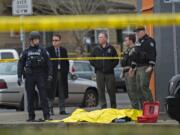 Vancouver police and Clark County Sheriff's deputies stand at the scene of a fatal officer-involved shooting at the corner of West 12th Street and Jefferson Street in downtown Vancouver on Thursday afternoon. The officer at the left appears to be standing over two firearms.