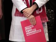 Dr. Erin Berry, Washington State Medical Director for Planned Parenthood of the Great Northwest and the Hawaiian Islands, holds a folder as she listens at a news conference announcing a lawsuit challenging the Trump administration's Title X "gag rule" Monday, Feb. 25, 2019, in Seattle. The rule issued last Friday would impact federal funding for reproductive health care and family planning services.