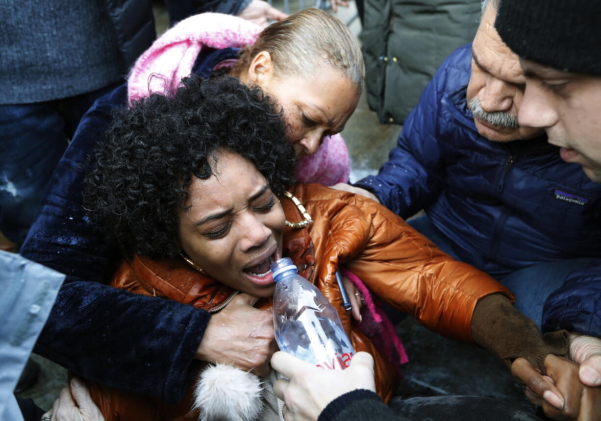 A woman is helped by others Sunday after she was sprayed with pepper spray after she and others stormed the main entrance to the Metropolitan Detention Center, a federal prison where prisoners have gone without heat, hot water and flushing toilets due to an electrical outage in the Brooklyn borough of New York.