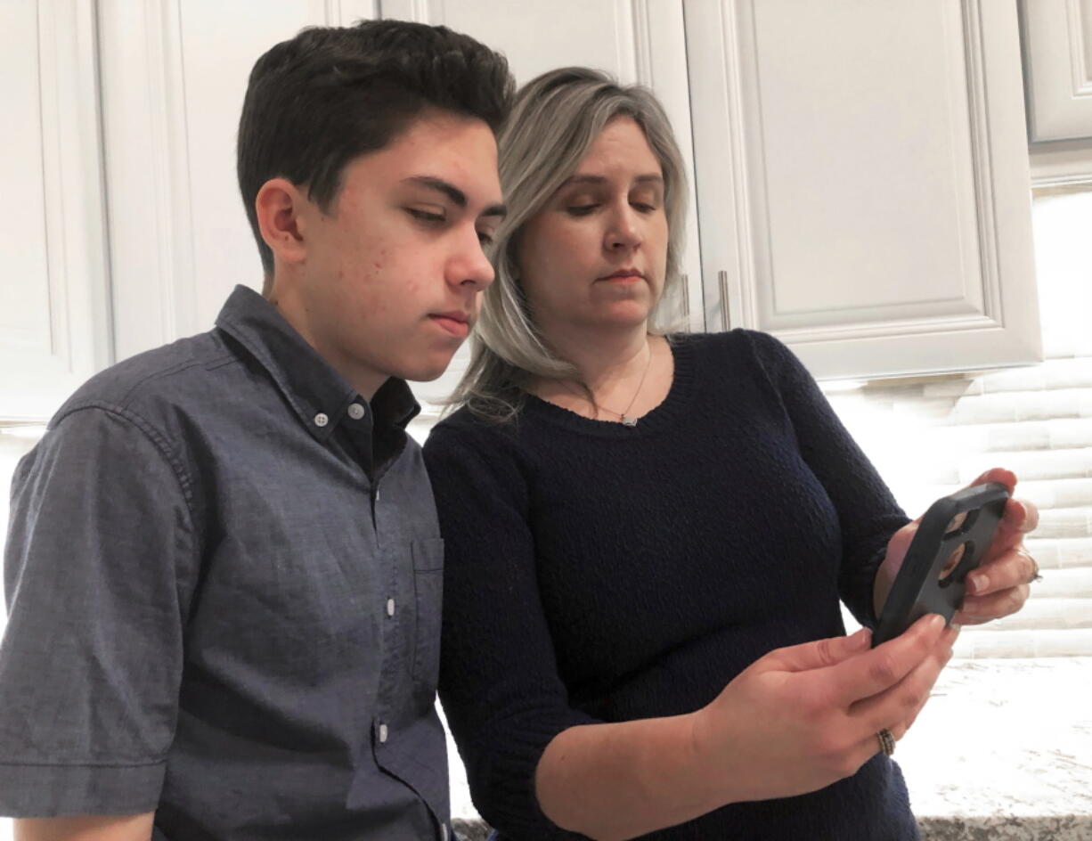 Grant Thompson and his mother, Michele, look at an iPhone in the family’s kitchen in Tucson, Ariz., on Thursday, Jan. 31, 2019. The 14-year-old stumbled upon a bug in the iPhone’s FaceTime group-chatting feature on Jan. 19 while calling his friends to play a video game. With the bug, a FaceTime group-chat user calling another iPhone, iPad or Mac computer could hear audio, even if the receiver did not accept the call.