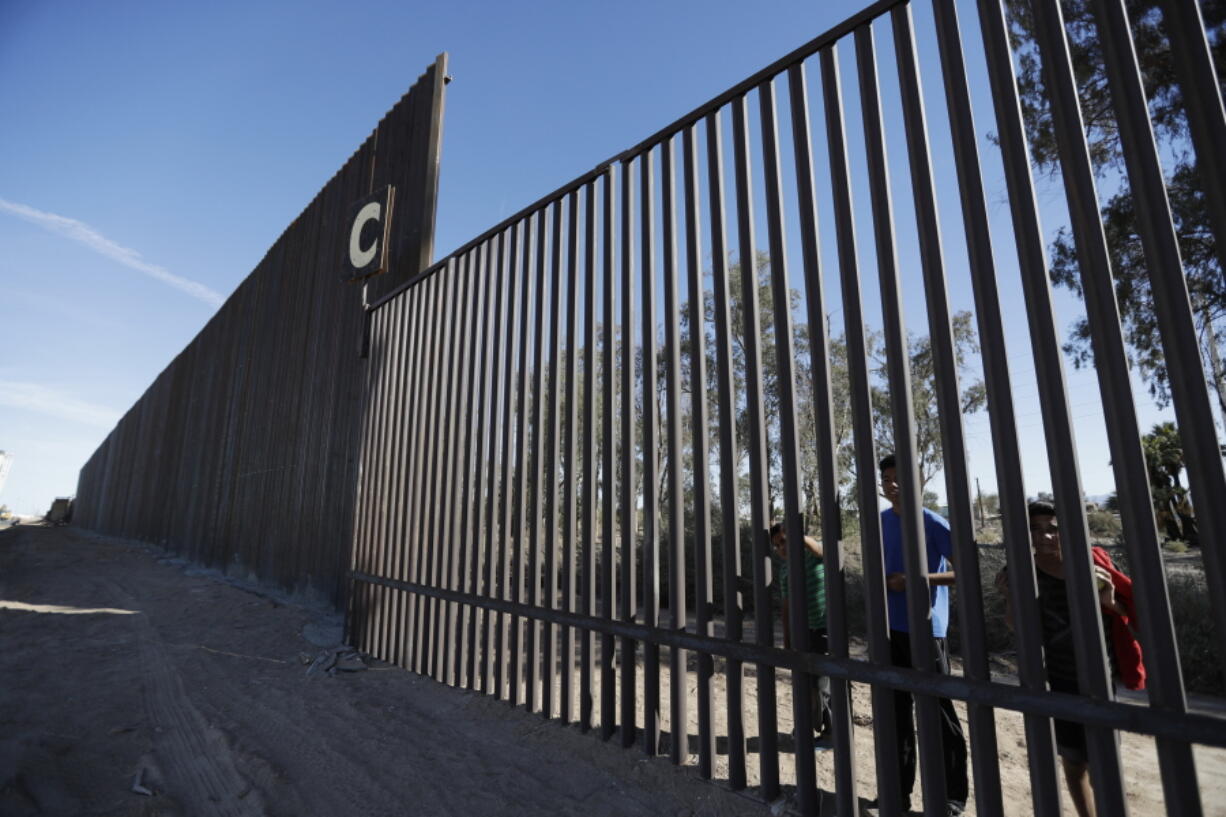 FILE - In this March 5, 2018, file photo, boys look through an older section of the border structure from Mexicali, Mexico, alongside a newly-constructed, taller section, left, in Calexico, Calif. A federal appeals court has rejected arguments by the state of California and environmental groups who tried to block reconstruction of sections of the U.S.-Mexico border wall. The 9th U.S. Circuit Court of Appeals ruled Monday, Feb. 11, 2019, that the Trump administration did not exceed its authority by waiving environmental regulations to rebuild sections of wall near San Diego and Calexico.