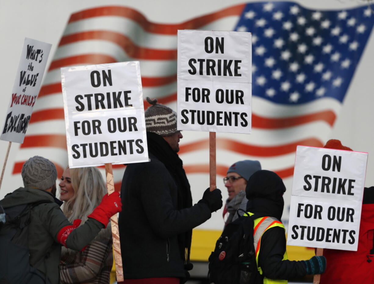 Teachers carry placards as they walk a picket line outside South High School early Monday, Feb. 11, 2019, in Denver. The strike on Monday is the first for teachers in Colorado in 25 years after failed negotiations with the school district over base pay.