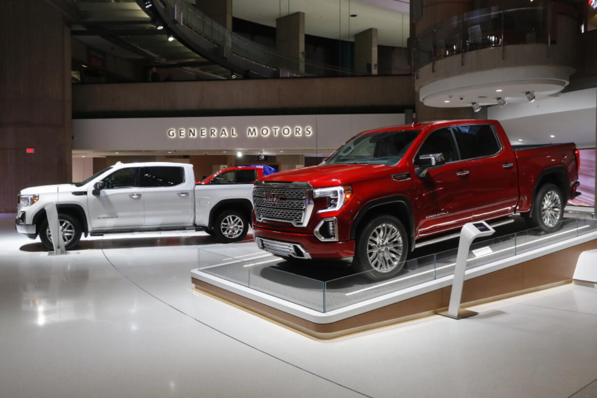 FILE- This Jan. 16, 2019, file photo shows a GMC Sierra pickup, left, and Denali in Detroit. General Motors’ posted an $8.1 billion net profit last year as it got better prices for vehicles sold in the U.S., its most lucrative market.