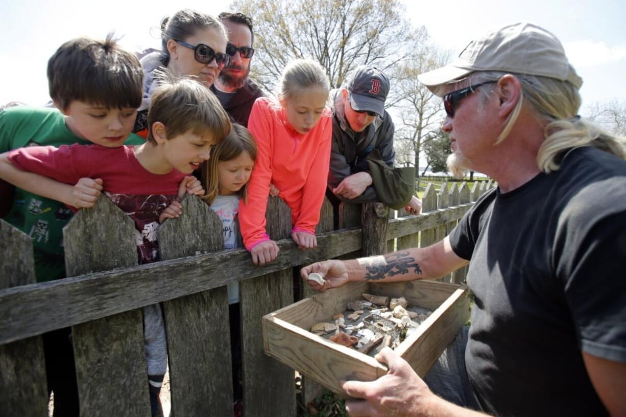 FILE - In this April 10, 2018, file photo, Historic Jamestowne staff archaeologist Lee McBee, right, shows artifacts to Carla Howe, of Gilmanton, N.H., left, and her children Caroline, second from left, and Grace, third from left, at the dig site of the Angelo slave house in Jamestown, Va. The first Africans to arrive in North America were so little noted by history that many are known today by only their first names.