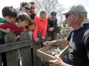 FILE - In this April 10, 2018, file photo, Historic Jamestowne staff archaeologist Lee McBee, right, shows artifacts to Carla Howe, of Gilmanton, N.H., left, and her children Caroline, second from left, and Grace, third from left, at the dig site of the Angelo slave house in Jamestown, Va. The first Africans to arrive in North America were so little noted by history that many are known today by only their first names.