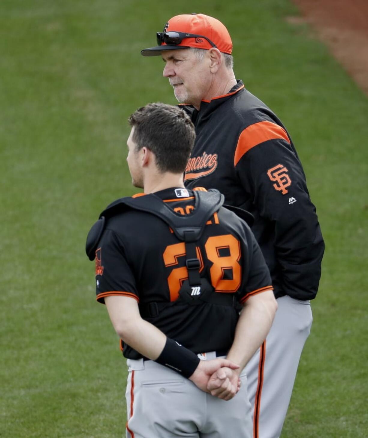 San Francisco Giants manager Bruce Bochy, top, talks with catcher Buster Posey during a baseball spring training practice, Wednesday, Feb. 13, 2019, in Scottsdale, Ariz.