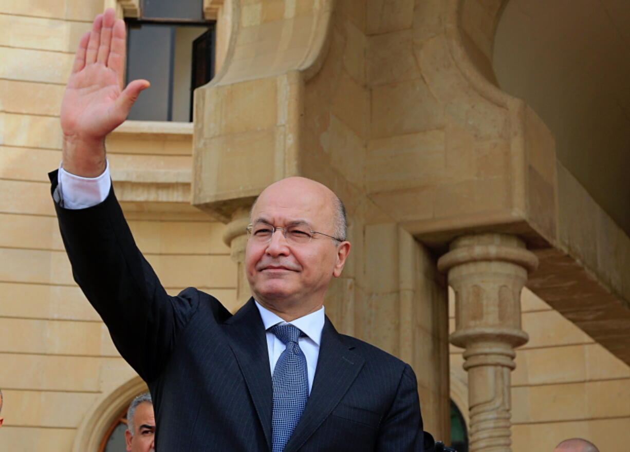 FILE - In this Oct. 11, 2018 file photo, Iraqi President Barham Salih waves goodbye to Turkish Foreign Minister Mevlut Cavusoglu, after their meeting in Baghdad, Iraq. Salih speaking Monday, Feb. 4, 2019, at a forum in Baghdad slammed comments by U.S. President Donald Trump in which he said he wants to keep U.S. troops in Iraq “to watch Iran.” Salih said the U.S. president did not ask Iraq’s permission for American troops stationed there to watch Iran. He said the Iraqi constitution forbids the use of Iraq as a base to threaten the interests or security of neighboring countries.