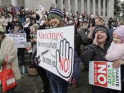 Lacey Walter of Kennewick holds a sign that reads “Vaccines, the more you know, the more you No!” on Friday, Feb. 8, at the Capitol in Olympia at a rally opposing a proposed bill that would remove the ability of parents of school-age children to claim a philosophical exemption to opt out of the combined measles, mumps and rubella vaccine. (Ted S.