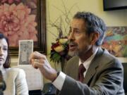 Dr. Gary Goldbaum of the Washington State Medical Association holds up a picture of his brother as a child, when he was in a wheelchair due to polio, at Wednesday’s hearing on a vaccination bill.