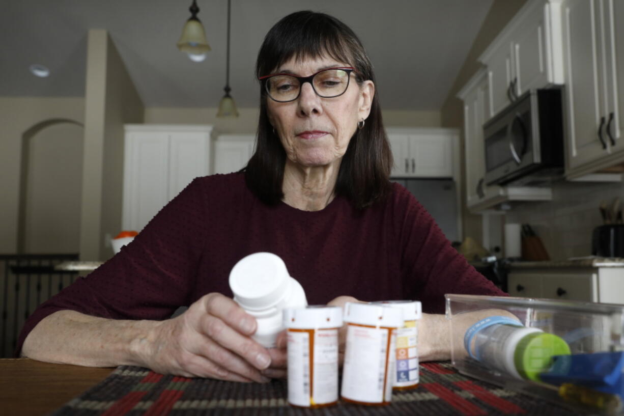 Retired public school teacher Gail Orcutt of Iowa looks over some of the prescription drugs she takes. Orcutt pays $2,600 the first month of the year, and then $750 every other month for a lung cancer medication. She said it cost more last year for a different drug.