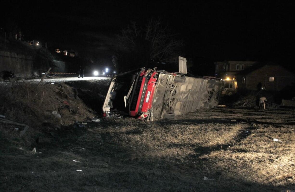 A bus sits overturned at a crash site Wednesday in Laskarci, North Macedonia. Fourteen people were killed.