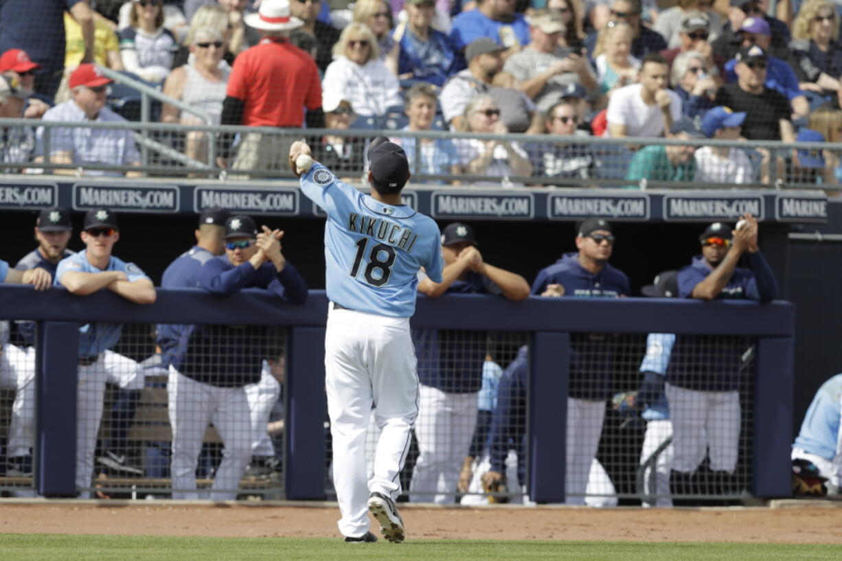 Seattle Mariners' Yusei Kikuchi tosses a baseball to fans during the first inning of a spring training baseball game against the Cincinnati Reds, Monday, Feb. 25, 2019, in Peoria, Ariz.