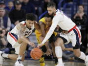 Gonzaga forward Brandon Clarke, left, guard Josh Perkins, right, and San Francisco guard Jamaree Bouyea go after the ball during the first half of an NCAA college basketball game in Spokane, Wash., Thursday, Feb. 7, 2019.