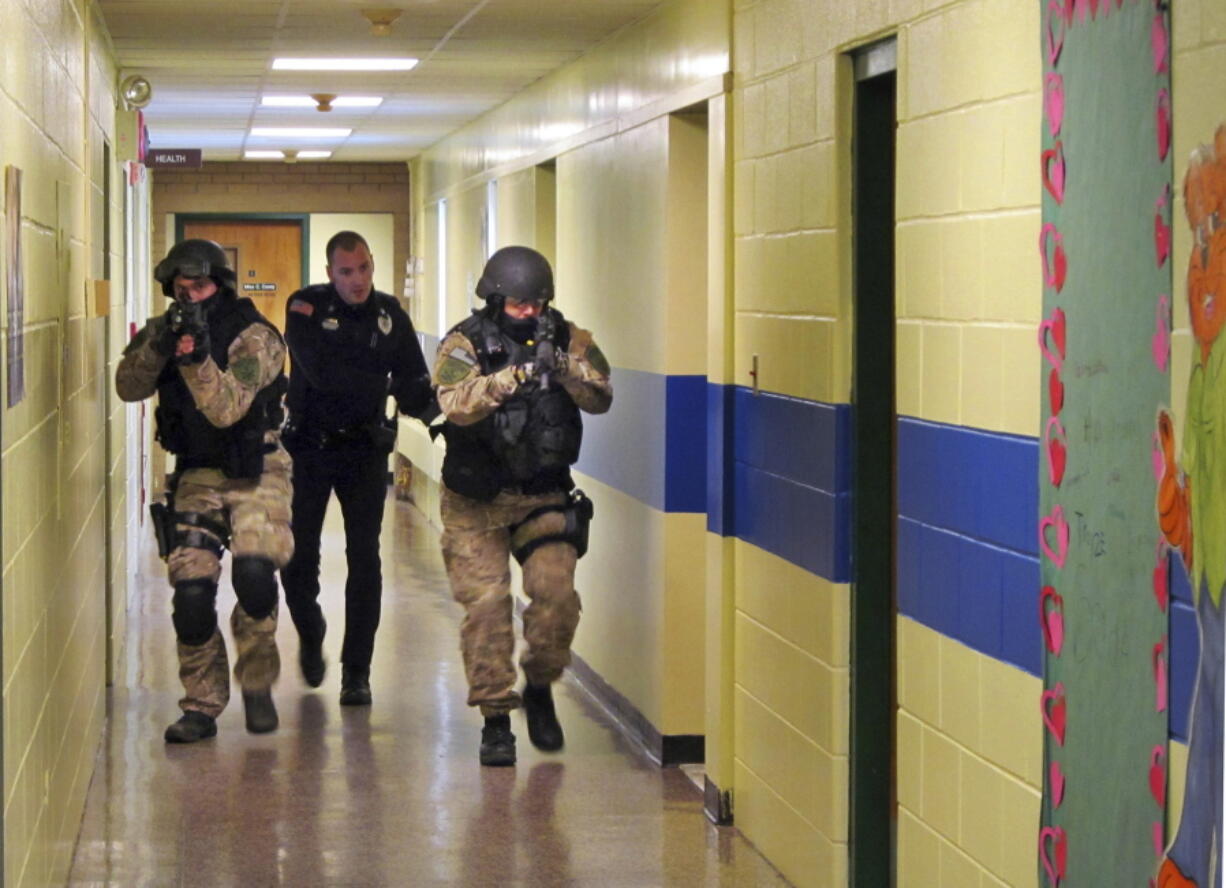 Members of the Washington County Sheriff’s Office and the Hudson Falls Police Department use unloaded guns to take part in an emergency drill Jan. 28, 2013, as they walk through a corridor inside the Hudson Falls Primary School in Hudson Falls, N.Y. With each subsequent shooting forcing schools to review their readiness, parents are increasingly questioning elements of the ever-evolving drills that are now part of most emergency plans, including the use of simulated gunfire and blood, when to reveal it’s just practice, and whether drills unduly traumatize kids.