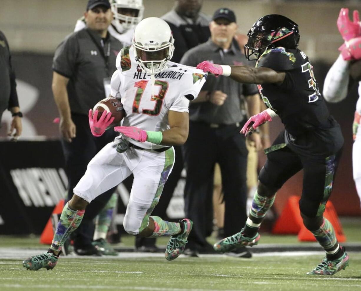 Running back Jerrion Ealy, left, gets snagged by a defender during the Under Armour All America Game in Orlando, Fla. Some drama on signing day might be drummed up around the few remaining unsigned five-star prospects. Darnell Wright, an offensive lineman from West Virginia, is expected to choose between Tennessee and Alabama. Ealy, a running back from Mississippi, will pick between Clemson and Ole Miss.