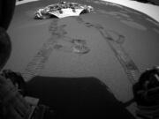 FILE - This photo released Thursday, Feb. 5, 2004 made by one of the rear hazard-avoidance cameras on NASA’s Opportunity rover, shows Opportunity’s landing platform, with freshly made tracks leading away from it. Opportunity rolled about 11 feet on Thursday, the first day it has moved since it left the lander on Saturday. Engineers commanded Opportunity to turn slightly during the drive, to test how it steers while rolling through the martian soil.