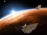 The twin Mars Cube One spacecraft fly over Mars with Earth and the sun in the distance.