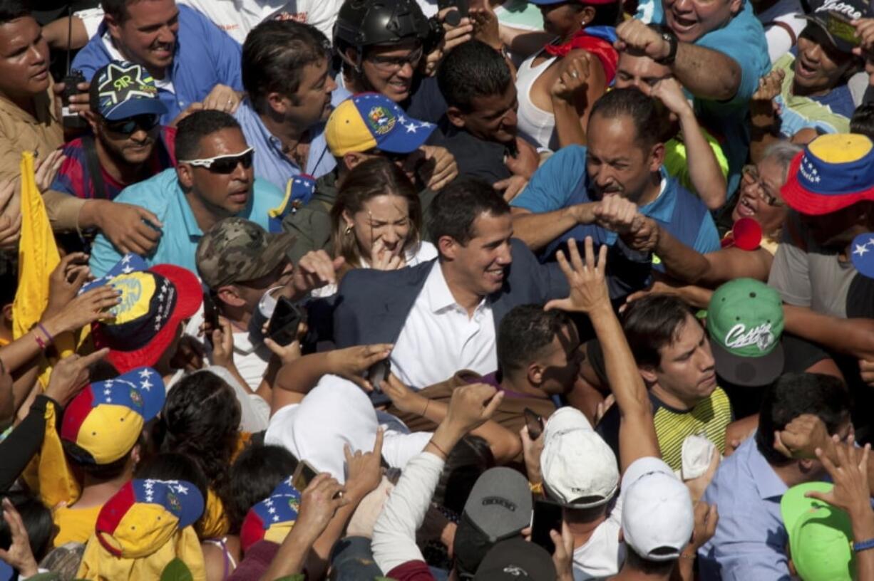 Venezuelan opposition leader Juan Guaido, center, who has declared himself the interim president of Venezuela, greets supporters as he arrives at a demonstration demanding the resignation of President Nicolas Maduro, in Caracas, Venezuela, Saturday.