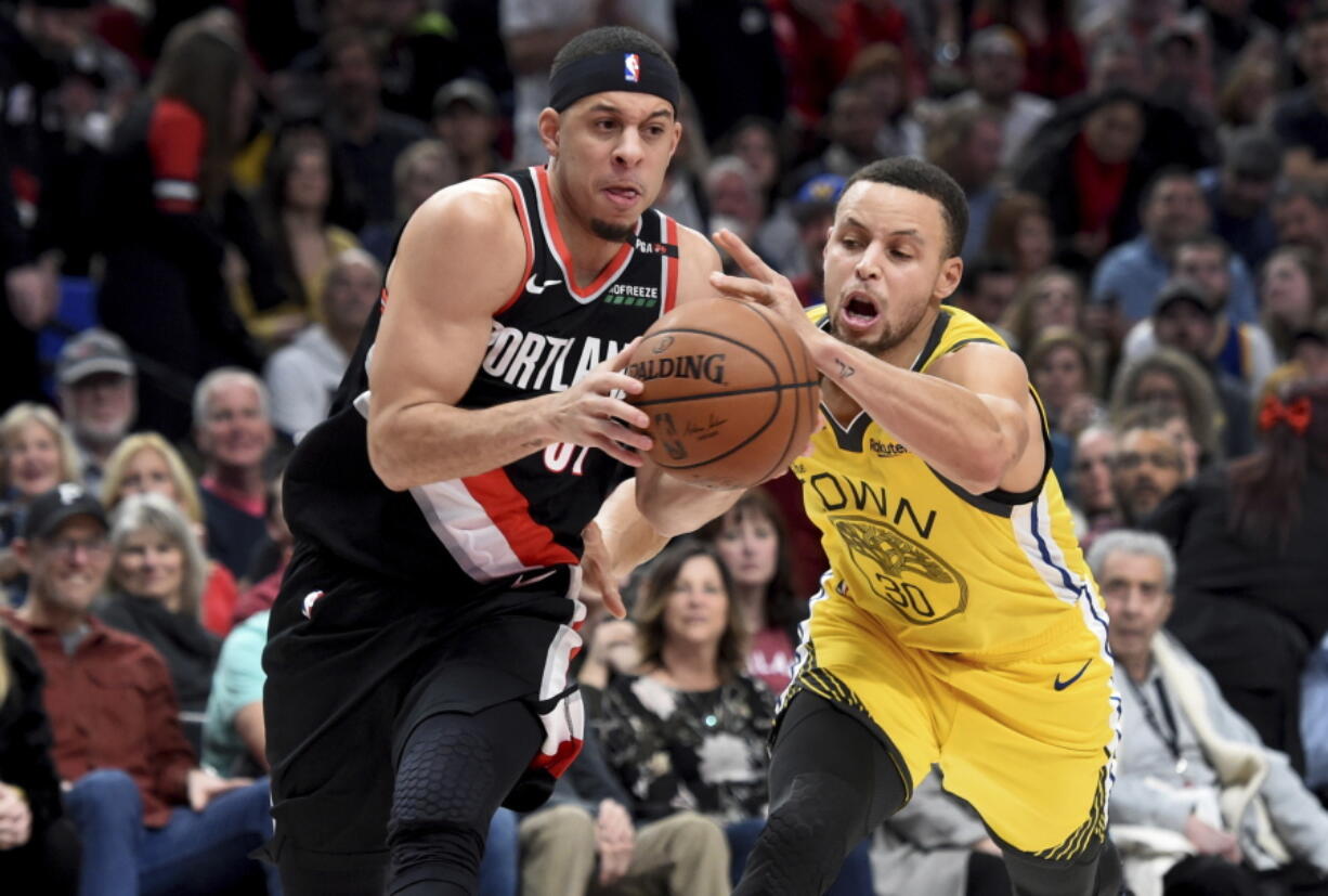 Portland Trail Blazers guard Seth Curry, left, drives to the basket on Golden State Warriors guard Stephen Curry during the second half of an NBA basketball game in Portland, Ore., Wednesday, Feb. 13, 2019. The Blazers won 129-107.