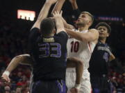 Arizona forward Ryan Luther (10) jumps for the basket while defended by Washington forward Sam Timmins (33) and guard Matisse Thybulle (4) in the first half of an NCAA college basketball game in Tucson, Ariz., Thursday, Feb. 7, 2019.