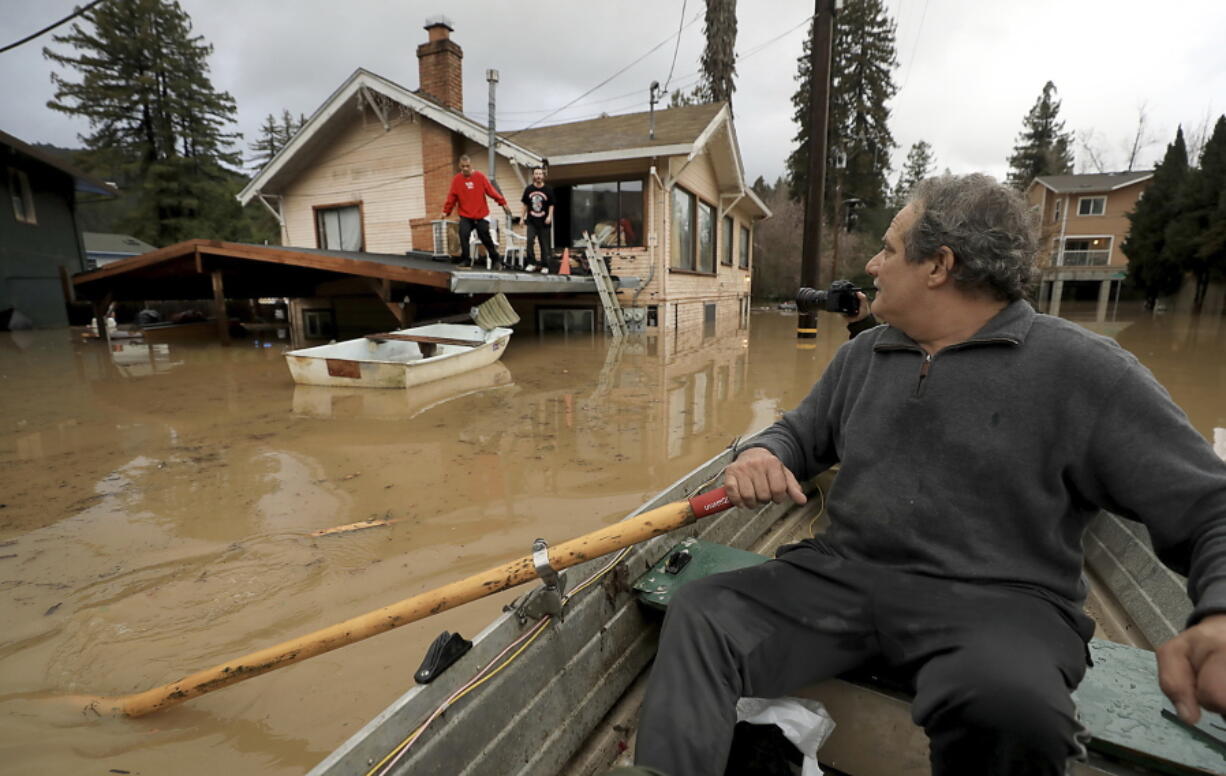 Jonathan Von Renner checks on his son Jonathan Jr., and friend Emilio Ontivares in lower Guerneville, Calif., Wednesday, Feb. 27, 2019. Two Northern California communities are accessible only by boat after a rain-swollen river overflowed its banks following a relentless downpour. The Sonoma County Sheriff’s Office says Guerneville, “is officially an island” and another nearby town was also isolated by floodwaters.