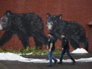 Washougal residents Shaun Humes, left, and Al Seaman stroll past a festive mural on their way to lunch in downtown Washougal on Feb. 11 as leftover snow melts nearby. The city is No. 7 on a list of the state’s safest.