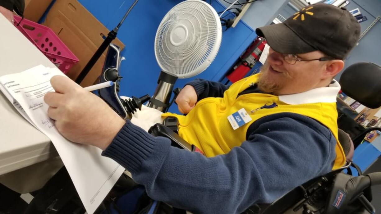 John Combs, the disabled Walmart greeter who feared losing his position over job-description changes, signs paperwork Wednesday for a different assignment within the Southeast 192nd Avenue store in Vancouver.