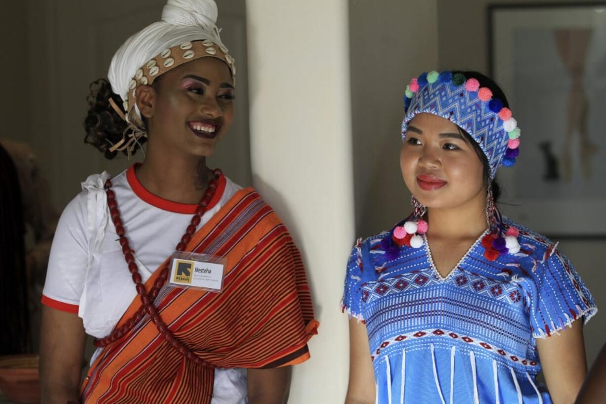 Nesteha Hassen, 17, left, of Ethiopia and Ywahay Moo, 16, of Thailand are dressed in native garb waiting to walk the runway at a fashion show in Leucadia featuring young women who are recent refugees to the United States.