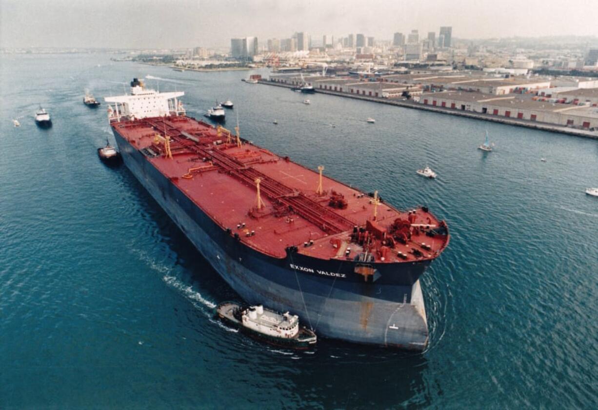 The beleaguered Exxon Valdez, escorted by tugs and Coast Guard vessels, makes its way through San Diego Bay to the shipyard of its birth, where the tanker underwent repairs four months after the massive Alaska oil spill. Print stamped July 31, 1989.