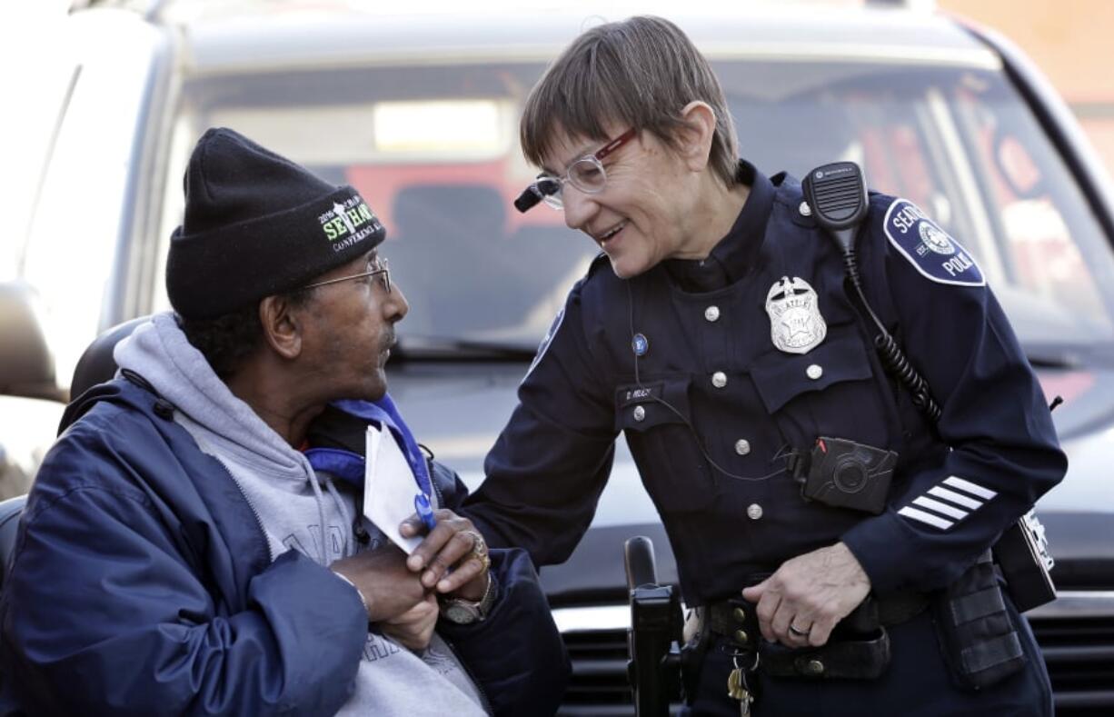 Seattle police Officer Debra Pelich, right, wears a video camera on her eyeglasses as she talks with Alex Legesse before a small community gathering in Seattle in 2015. While the Seattle Police Department bars officers from using real-time facial recognition in body camera video, privacy activists are concerned that a proliferation of the technology could turn the cameras into tools of mass surveillance. The ACLU and other organizations in May 2018 asked Amazon to stop selling its facial-recognition tool, called Rekognition, to law enforcement agencies.