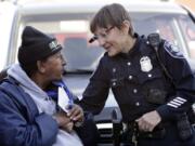 Seattle police Officer Debra Pelich, right, wears a video camera on her eyeglasses as she talks with Alex Legesse before a small community gathering in Seattle in 2015. While the Seattle Police Department bars officers from using real-time facial recognition in body camera video, privacy activists are concerned that a proliferation of the technology could turn the cameras into tools of mass surveillance. The ACLU and other organizations in May 2018 asked Amazon to stop selling its facial-recognition tool, called Rekognition, to law enforcement agencies.