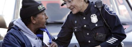 Seattle police Officer Debra Pelich, right, wears a video camera on her eyeglasses as she talks with Alex Legesse before a small community gathering in Seattle in 2015. While the Seattle Police Department bars officers from using real-time facial recognition in body camera video, privacy activists are concerned that a proliferation of the technology could turn the cameras into tools of mass surveillance. The ACLU and other organizations in May 2018 asked Amazon to stop selling its facial-recognition tool, called Rekognition, to law enforcement agencies.