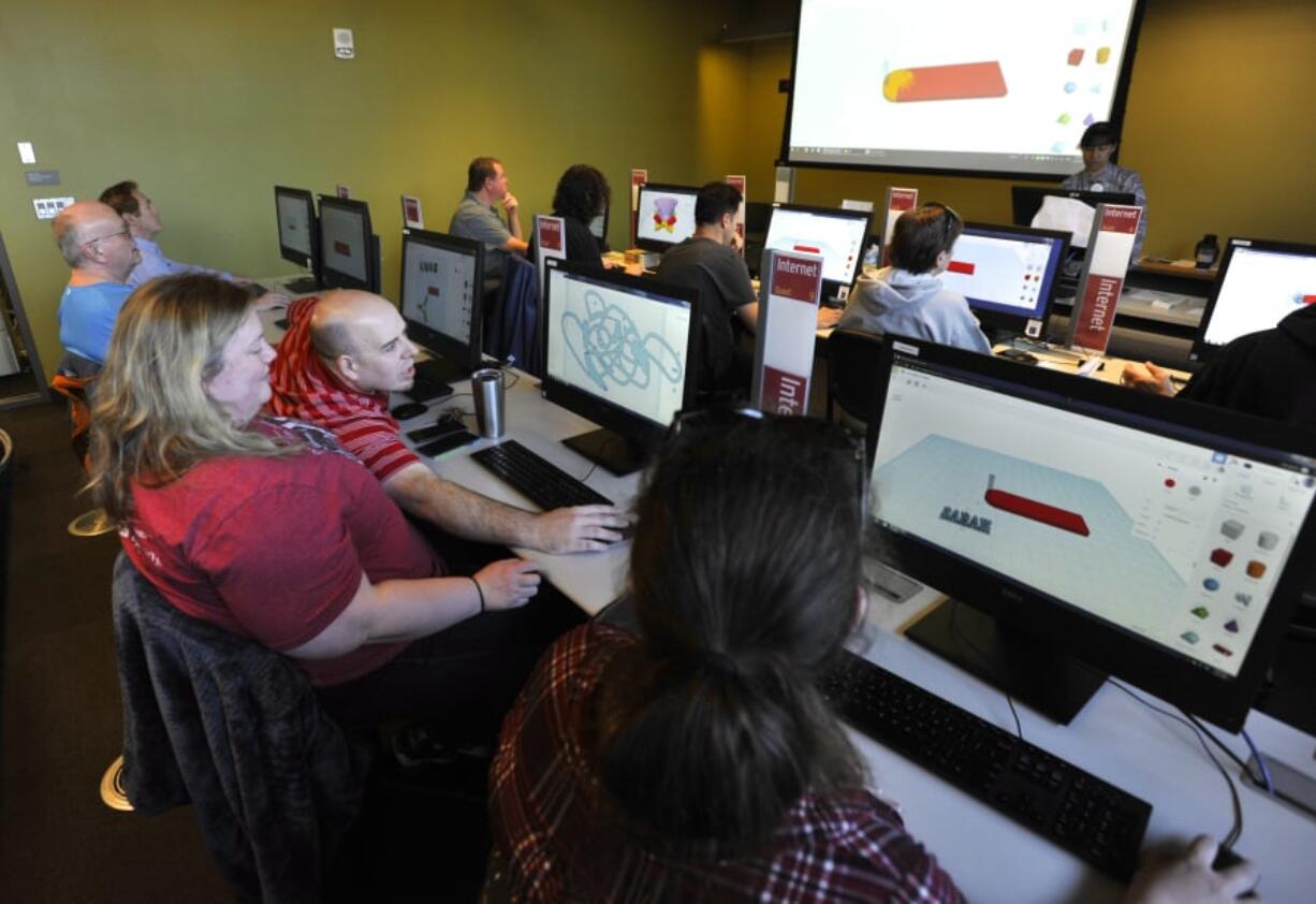 Stacey Loeffler, center, and Luke Looeffler consult about their designs at the Intro to 3D Design class at the Vancouver Community Library in Vancouver on Sunday.