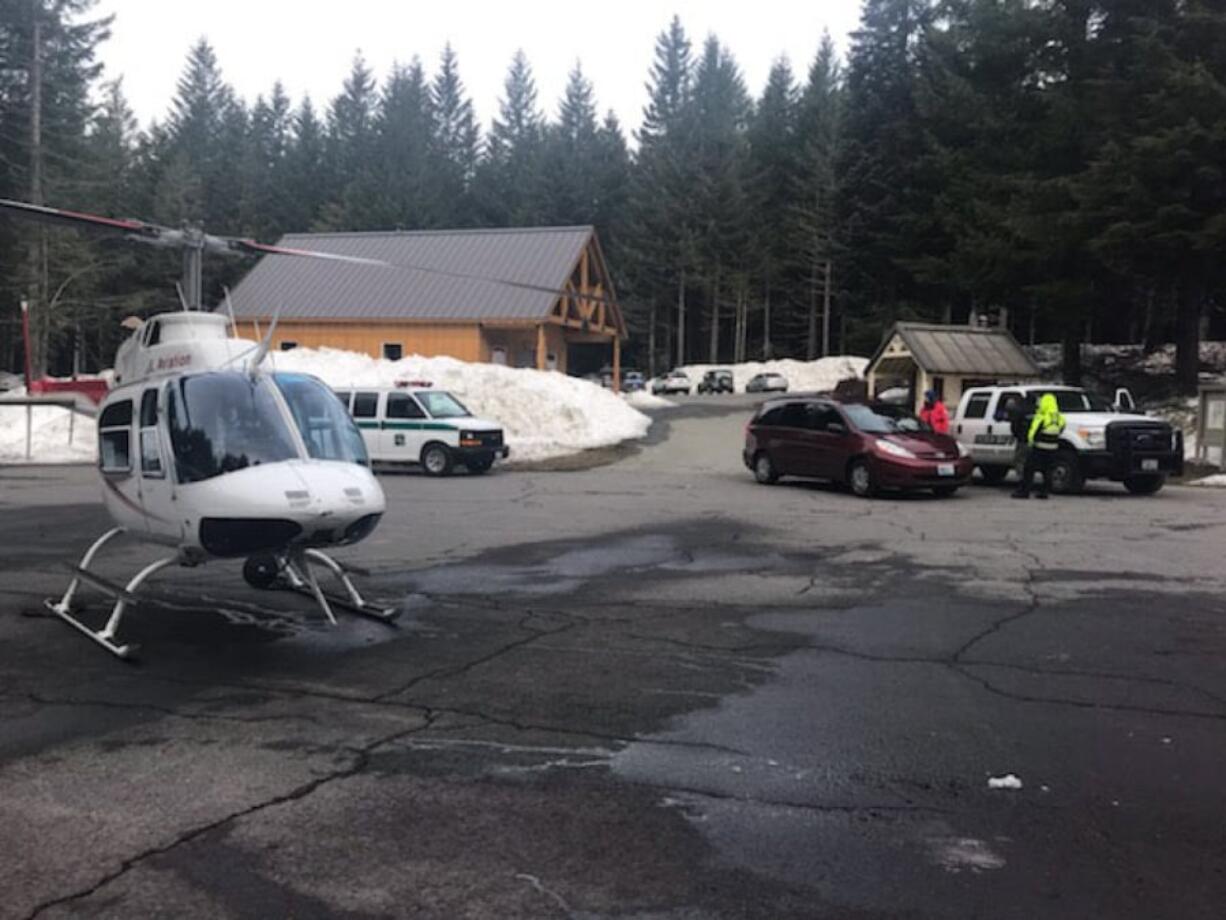 A helicopter and search-and-rescue personnel are seen at Marble Mountain Sno-Park as part of a rescue effort for two men who were stuck on Mount St. Helens overnight Sunday.