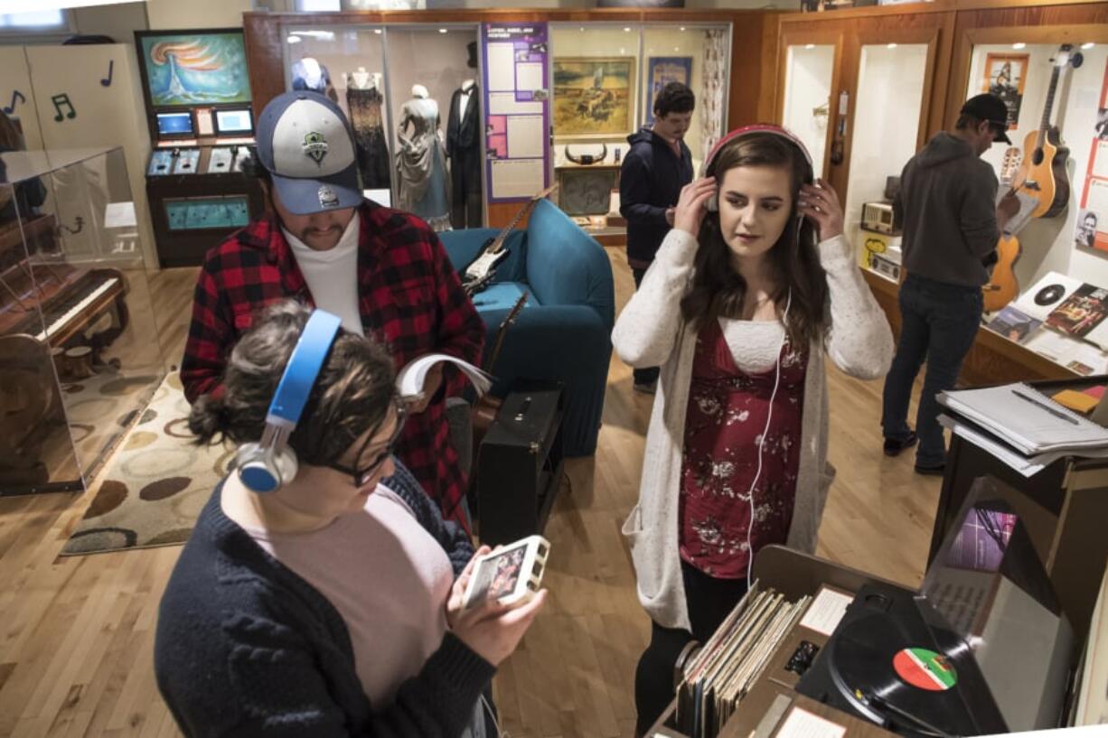 Washington State University Vancouver history students Ruby Burke, left, Brian Sanchez and Katie O’Boyle sample the sound technologies of yesteryear while studying “Music, Movement and Sound,” an interactive exhibit that opened in January at the Clark County Historical Museum.